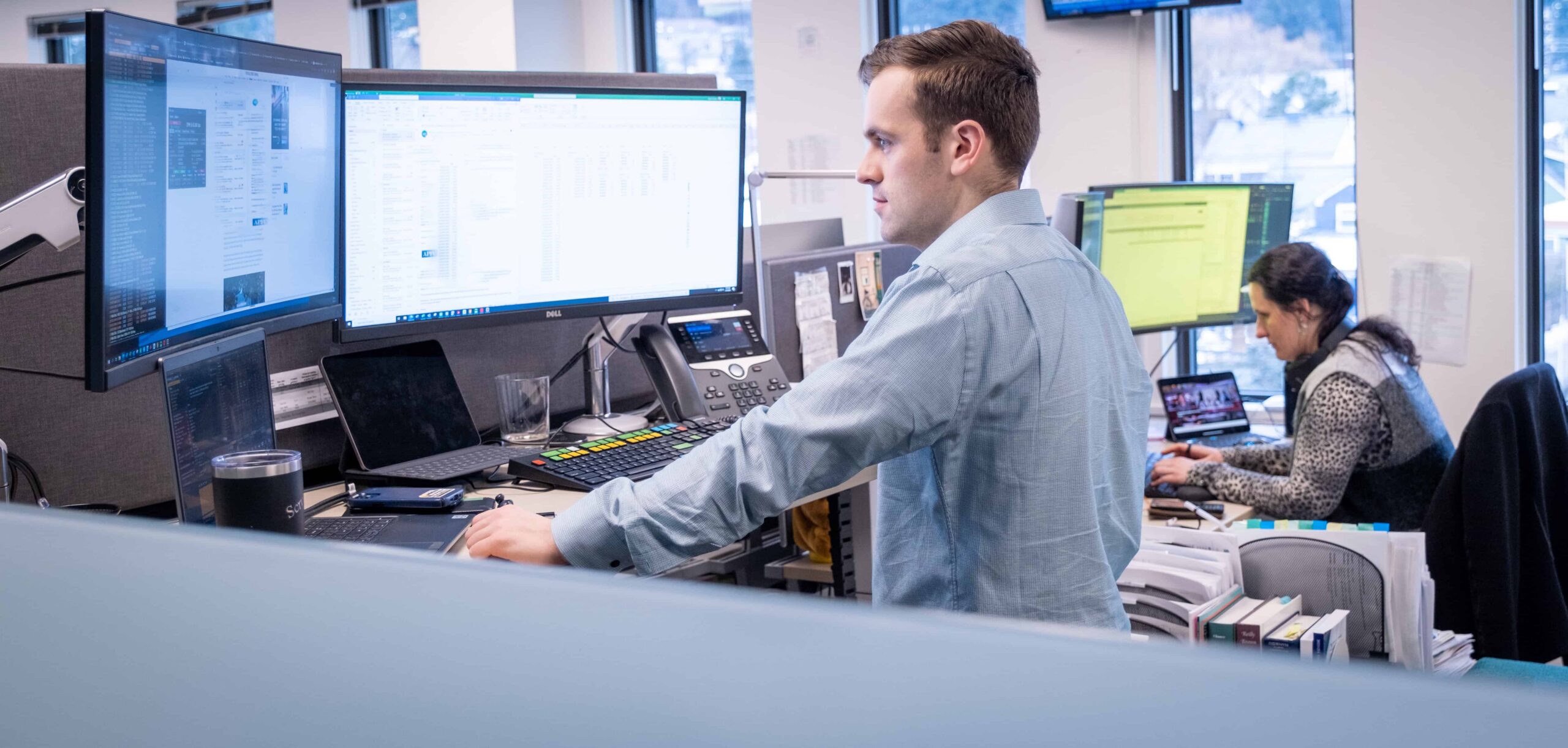 A man standing at a computer with investment information displayed