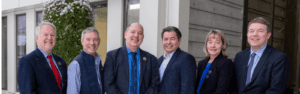 Six Board members standing outside the Michael J Burns Building